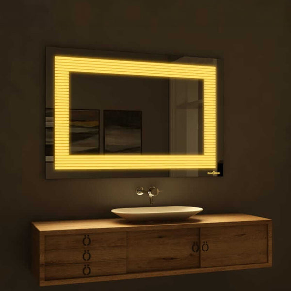 A rectangular bathroom mirror with warm yellow LED backlighting on the sides. The mirror is mounted on a bathroom wall above a porcelain sink with a chrome faucet.