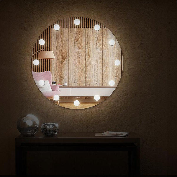Modern illuminated vanity mirror with small bulbs placed all around it. The mirror has a round shape with a frameless design. The bulbs are 3W each.
