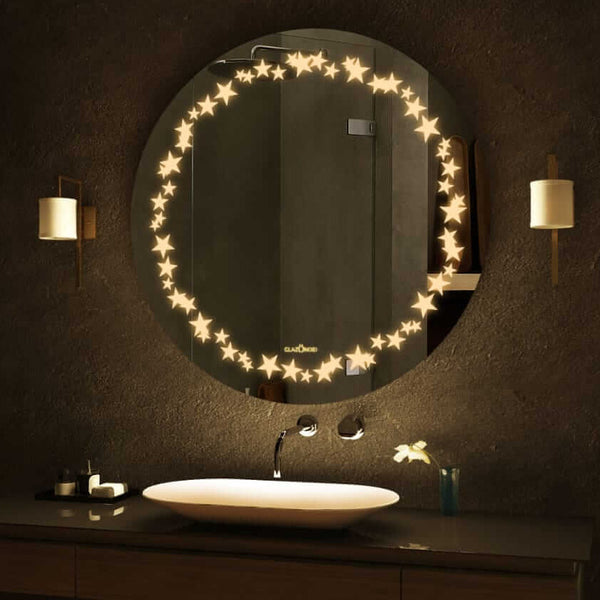 A round bathroom mirror with LED lights around the circumference. The mirror is mounted on a bathroom wall above a sink. There is text written on the bottom right corner of the mirror that says Glazonoid.