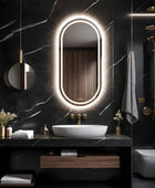A modern bathroom vanity with a black finish, polished chrome sink and a capsule shaped LED mirror with a dimmable LED light behind it. The mirror is mounted on the wall above the sink.