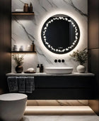 A whimsical bathroom with a round mirror decorated with LED stars in a circle, a white ceramic sink and a toilet. Great for a classic bathroom design.