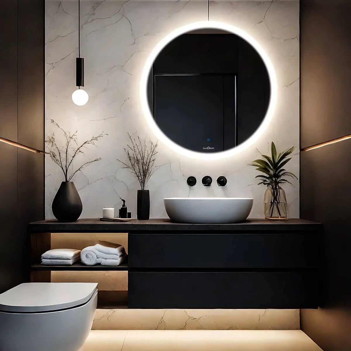 A classic bathroom with a white ceramic sink, toilet, and a round LED mirror. There is a black and white patterned shower curtain in the background. This simple and elegant bathroom design is perfect for any home. This timeless design is both stylish and functional.