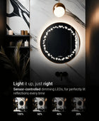 A round bathroom mirror with a built-in circle of star-shaped LED lights. The light is dimmable and sensor-controlled. Text on the mirror says 'Light it up, just right,' with dimming percentages below it.
