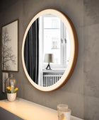 White dresser with a large round mirror with a stainless steel frame on top. The mirror is tilted slightly upwards. There is a small potted plant and a jewelry box on the dresser surface. This stylish dresser with mirror is perfect for any bedroom.