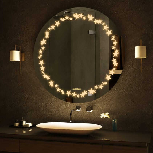 A round bathroom mirror with LED lights around the circumference. The mirror is mounted on a bathroom wall above a sink. There is text written on the bottom right corner of the mirror that says Glazonoid.