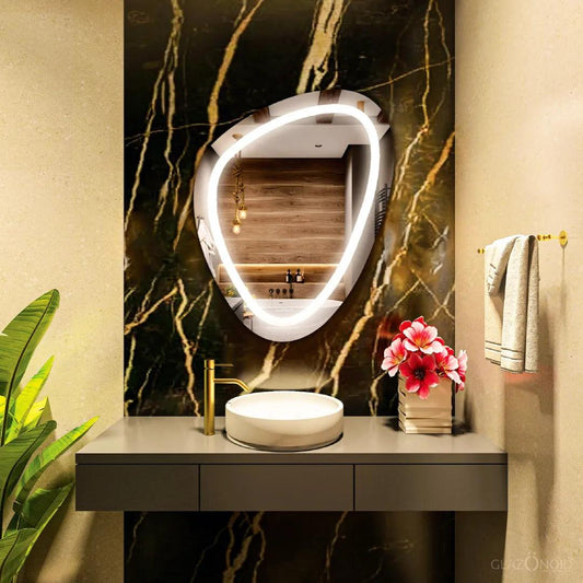 A close-up of a well-organized modern bathroom shelf featuring a white ceramic soap dispenser and two glass jars with chrome lids filled with cotton balls and cotton swabs, Along with a pebble shaped LED mirror with a nice and vibrant LED strip.