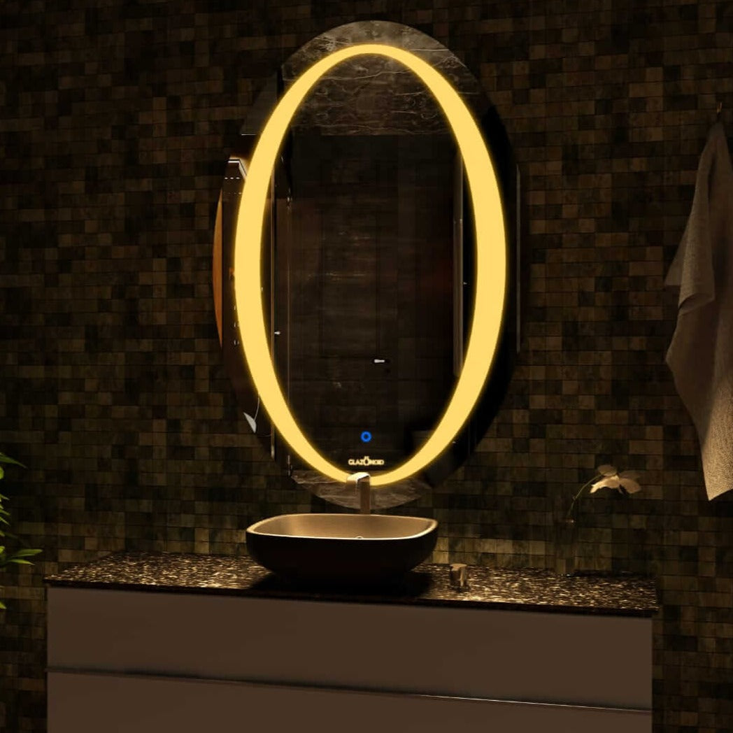 Modern bathroom mirror with a bright warm LED, in a oval shape with a chrome towel rack holding a white towel, above a white and black vanity and a black satin sink.