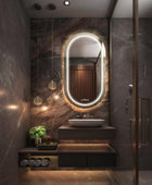 A modern bathroom vanity with a polished chrome faucet, a white ceramic sink, and a capsule LED mirror with a LED light behind it.